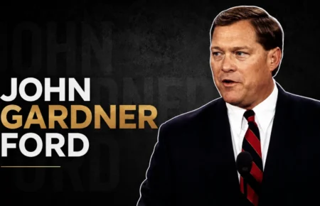 John Gardner Ford speaking at a podium in a formal suit