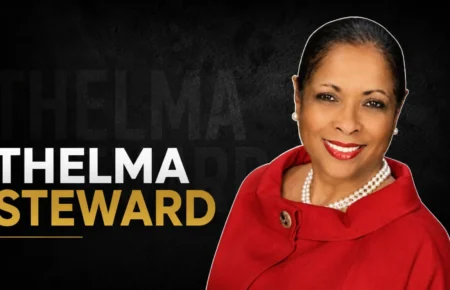 Thelma Steward wearing a red coat and pearl necklace